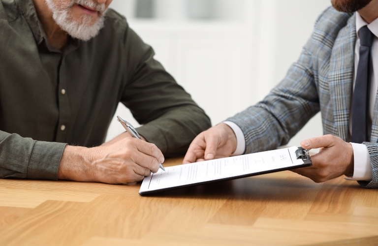 notary showing senior man where to sign document