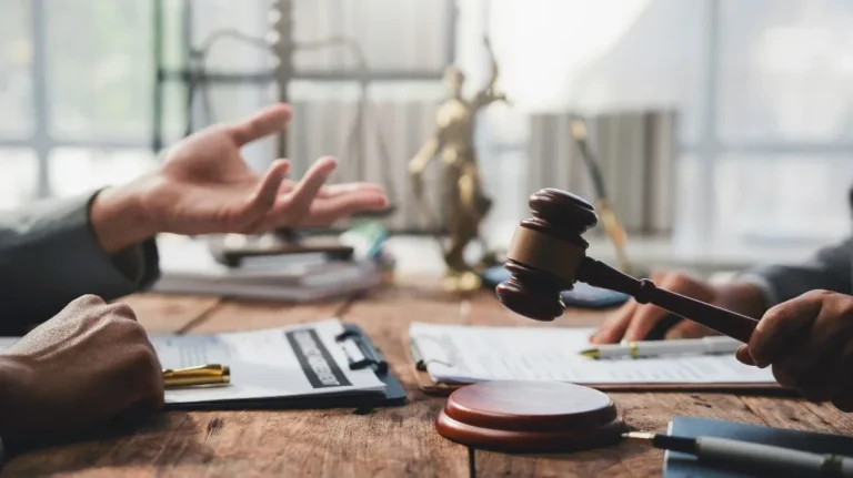 Two individuals engaged in a legal discussion with a judge's gavel and documents on a wooden table.