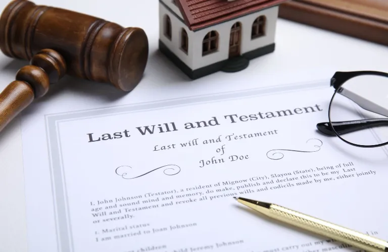Last Will and Testament document with a judge’s gavel, model house, pen, and eyeglasses.